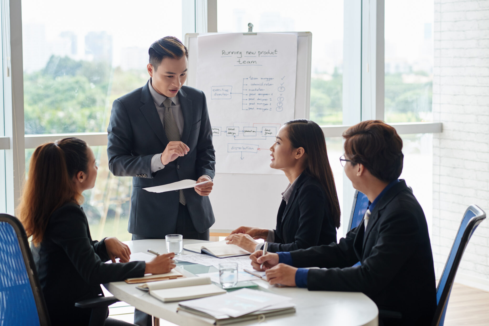 Male and female financial managers gathered together in spacious meeting room and analyzing statistical data, picturesque view on background